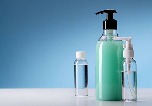 Hand hygiene disinfectants. Spray bottles on blue background, copy space. - Photo, Image