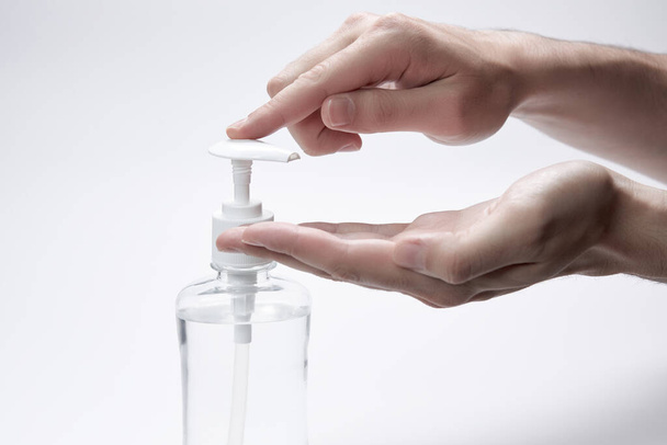 The finger presses in hand a bottle or container with liquid, cream or antiseptic on a white background. - Photo, image