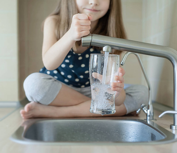 Little child open water tap. Kitchen faucet. Glass of clean water. Pouring fresh drink. Hydration. Healthy lifestyle, good habit. Water quality check. World water monitoring day. Plastic free concept - Photo, image