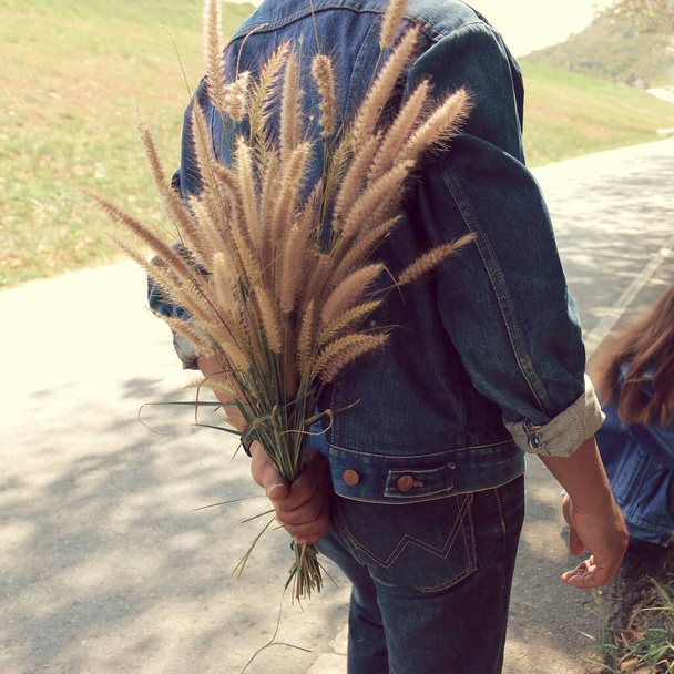 L'homme cache les fleurs d'herbe derrière son dos pour surprendre sa petite amie
. - Photo, image