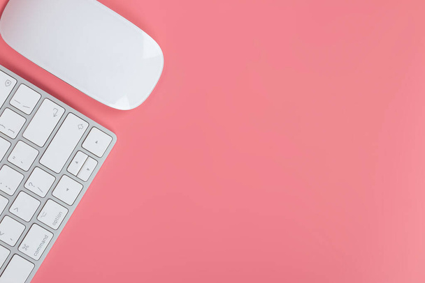 Platte lay, tafel tafel tafel boven. Werkruimte met toetsenbord en muis op roze achtergrond. - Foto, afbeelding