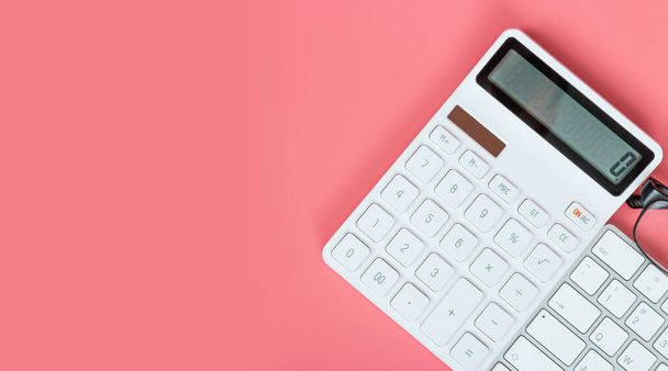 Женское рабочее место, клавиатура, белый калькулятор и очки на ярко-розовом фоне
. - Фото, изображение