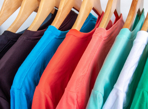 Fashion T-shirt su appendiabiti - Primo piano di luminoso armadio colorato su appendini in legno nel ripostiglio
 - Foto, immagini