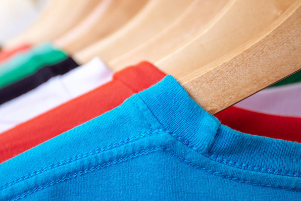 Fashion T-shirt su appendiabiti - Primo piano di luminoso armadio colorato su appendini in legno nel ripostiglio
 - Foto, immagini