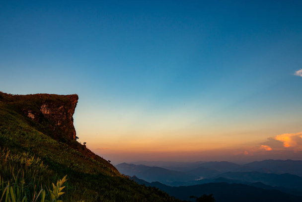 Τα ψηλά βράχια στα βουνά προεξέχουν στον ουρανό το ηλιοβασίλεμα. - Φωτογραφία, εικόνα