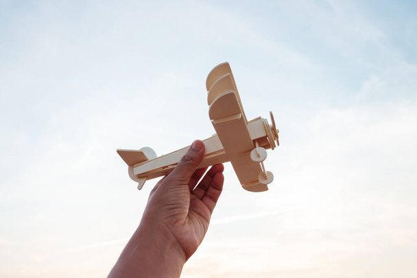 Svoboda koncept, lidská ruka drží dřevěné letadlo na pozadí západu slunce - Fotografie, Obrázek