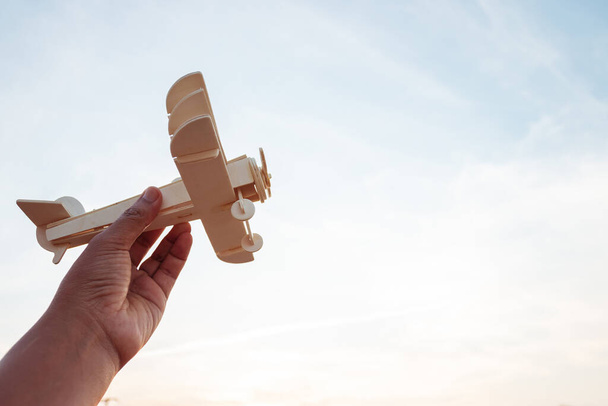 自由の概念は、日没の空の背景に木製の飛行機を保持人間の手 - 写真・画像
