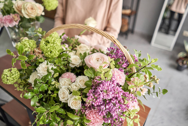 Floral shop concept . Florist woman creates flower arrangement in a wicker basket. Beautiful bouquet of mixed flowers. Handsome fresh bunch. Flowers delivery. - 写真・画像