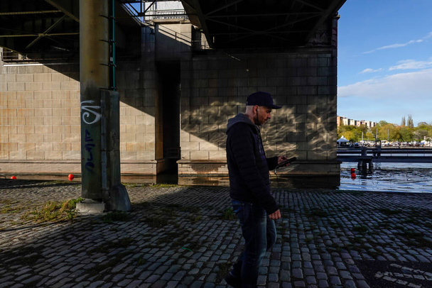 Stockholm, Švédsko Muž kráčí pod Liljeholmsbron a dívá se na svůj telefon. - Fotografie, Obrázek