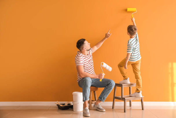 Petit fils aidant son père à peindre un mur à la maison
 - Photo, image