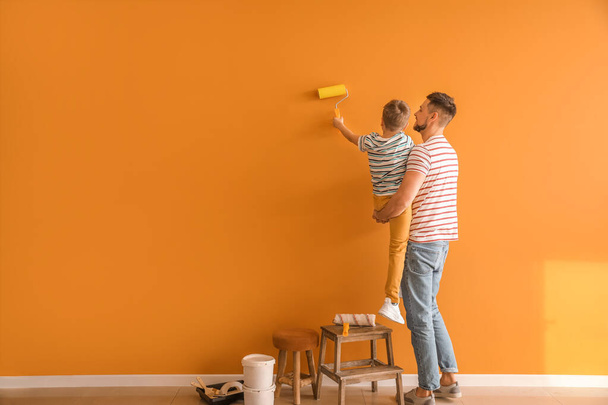 Little son helping his father to paint wall at home - Φωτογραφία, εικόνα