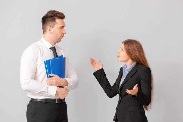 Wütende weibliche Chefin schimpft auf ihren männlichen Sekretär vor hellem Hintergrund - Foto, Bild
