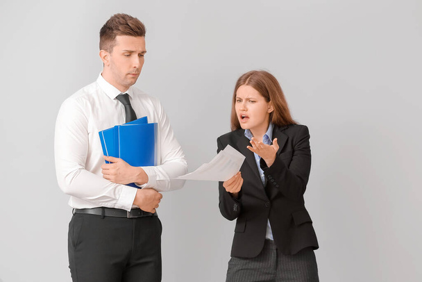 Angry female boss scolding her male secretary on light background - Photo, Image