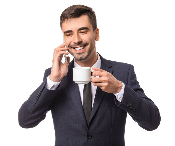Jovem empresário com xícara de café quente falando por telefone no fundo branco
 - Foto, Imagem