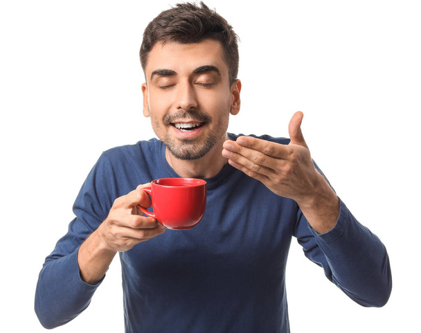 Hombre joven con taza de café caliente sobre fondo blanco
 - Foto, Imagen