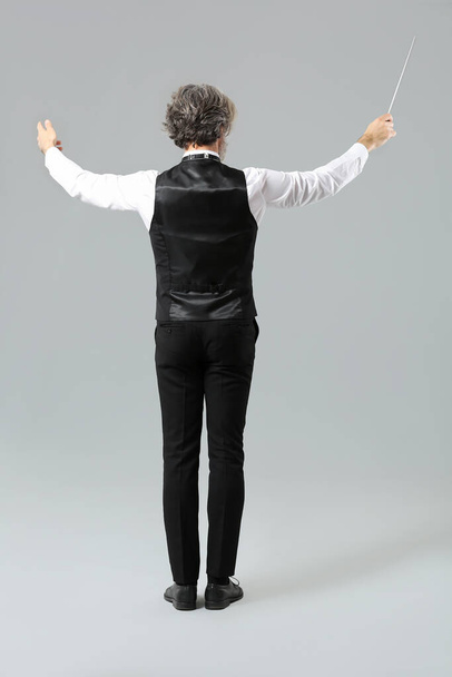 Senior male conductor on grey background - Valokuva, kuva