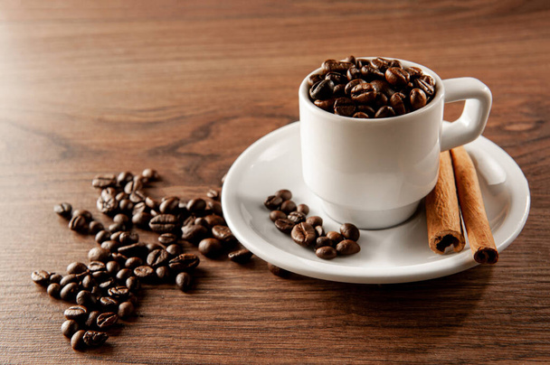 koffiebonen in een koffiekopje met kaneelstokjes - Foto, afbeelding