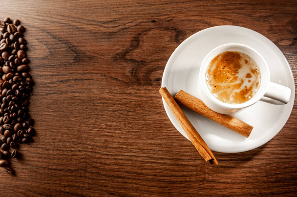 Dobré ráno. Šálek kávy, skořice a kávová zrna na dřevěném pozadí. Horní pohled. - Fotografie, Obrázek