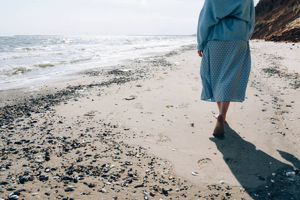 ドレスを着た女の子が海のそばの砂の上を歩いている。テキストの場所があります。. - 写真・画像