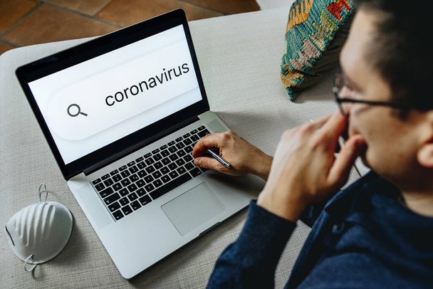 man stay informed about coronavirus during smart working on laptop at home. Fake news, internet, information concept. - Zdjęcie, obraz