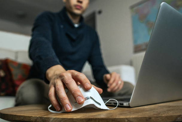 Zamknij biznesmena mądrego pracującego na laptopie w domu podczas brania maski ochronnej koronawirusa. Pandemia, koncepcja biznesowa. - Zdjęcie, obraz