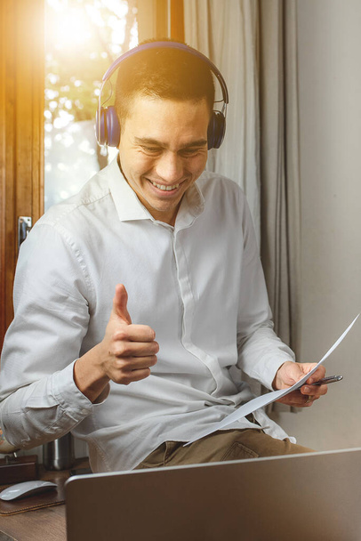 ノートパソコンで働くビジネスマンの肖像画。ヘッドフォンでビジネスビデオ通話で笑顔 - 写真・画像