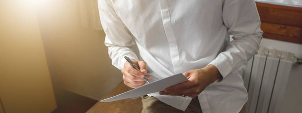 Horizontal banner Close-up of hand man holding paper and pen, taking notes. Businessman, office work concept. - Photo, Image