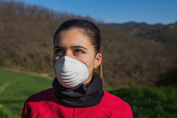 Muotokuva urheilullinen nuori nainen yllään kasvot suojaava naamio koronavirus pandemia. Ennen kuin teet liikuntaa ulkona ulkona. - Valokuva, kuva
