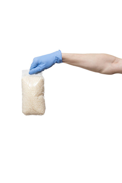 Man met blauwe handschoenen met pakje rijst. tas in de hand geïsoleerd op wit - Foto, afbeelding