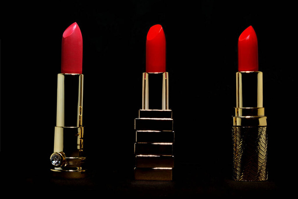 Red lipstick in gold slipcover on black background make up and cosmetic concept - Foto, immagini