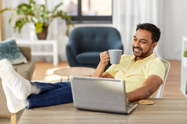 man with laptop drinking coffee at home office - Photo, Image