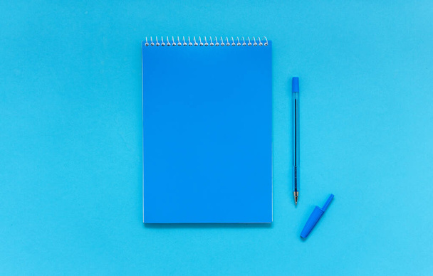 Mock up, blue notebook and pen on blue background. - Foto, afbeelding