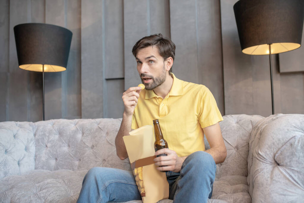 Interested man with open mouth with beer and chips. - Foto, Imagen