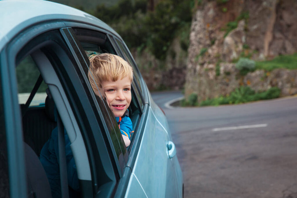happy cute boy travel by car in mountains, road trip vacation - Foto, afbeelding