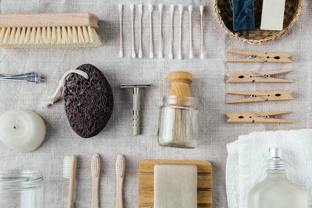 Everyday selfcare washing utencils nicely organized on natural linen fabric flat lay. Wooden brushes, bamboo toothbrushes, soap, parfume, razor, toothpaste, towel, clothespins and other accessories. - Фото, зображення