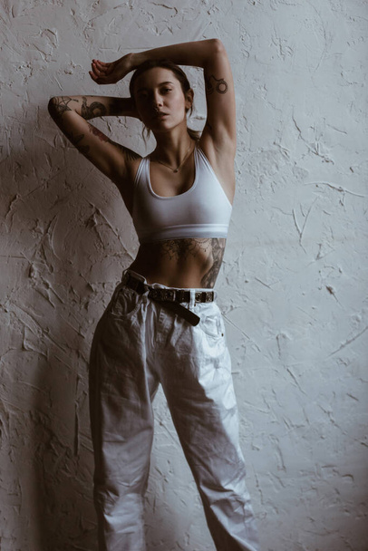 Sexy woman with tattoos wearing cotton bra and white jeans - Foto, immagini