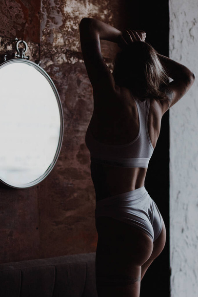 Back view of sexy woman wearing cotton lingerie standing near the mirror - Φωτογραφία, εικόνα