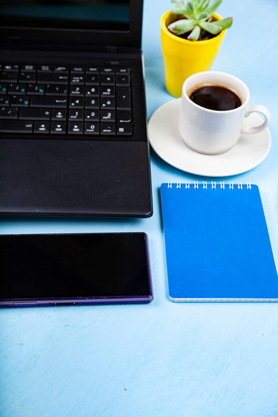 Business still life. Laptop, phone and coffee on a blue table. - Foto, imagen
