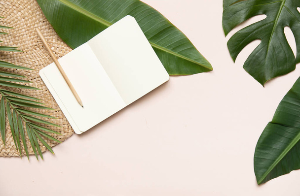 Fltlay-Konzept mit Textplatz in der Mitte und dem Rand des Notizbuchs, Bleistift mit rundem Weidenständer und tropischen Palmenblättern auf rosa Hintergrund - Foto, Bild