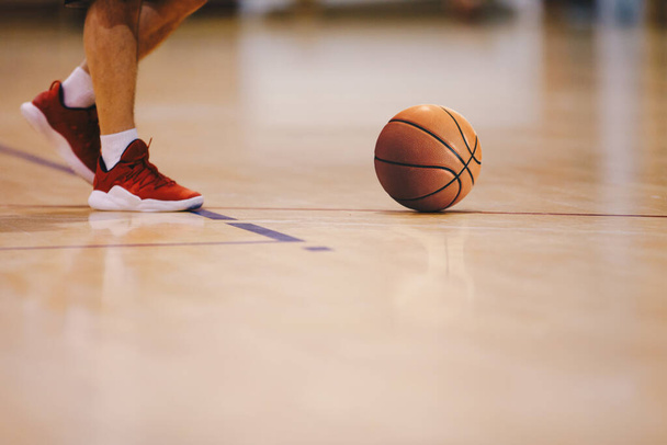 Basketball player walking on wooden court. Basketball over the floor. Basketball sports court - Photo, Image
