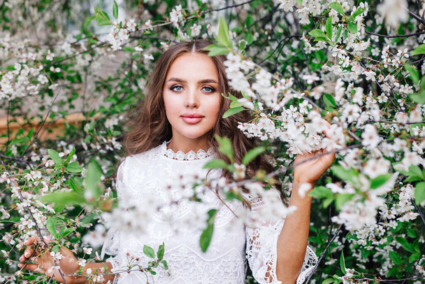 Beautiful young woman surrounded by spring flowers. - Fotó, kép