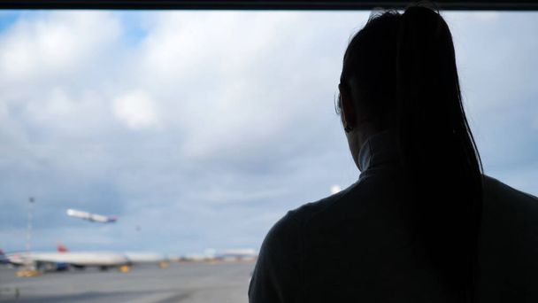 lány sziluett úgy néz ki, felszálló repülőgép a repülőtér közelkép - Fotó, kép