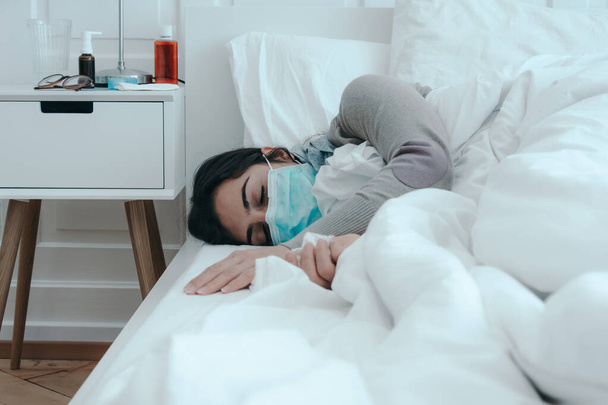 Young, sick woman sleeps in bed with a face mask on. - Foto, afbeelding