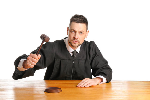 Αυστηρός αρσενικός δικαστής στο τραπέζι σε λευκό φόντο - Φωτογραφία, εικόνα