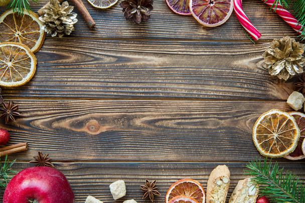 Christmas accessorizes objects on brown wooden background. Dried oranges, fir tree branches, golen connes, candies. Space for text. Copy space.  - Φωτογραφία, εικόνα