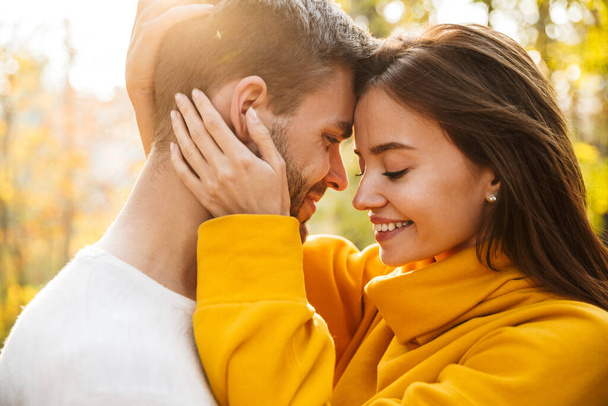 Primer plano de una hermosa pareja feliz joven enamorada abrazando mientras pasa tiempo en el parque de otoño
 - Foto, imagen