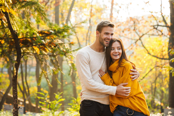 Beautiful young happy couple in love embracing while spending time in the autumn park - Фото, зображення