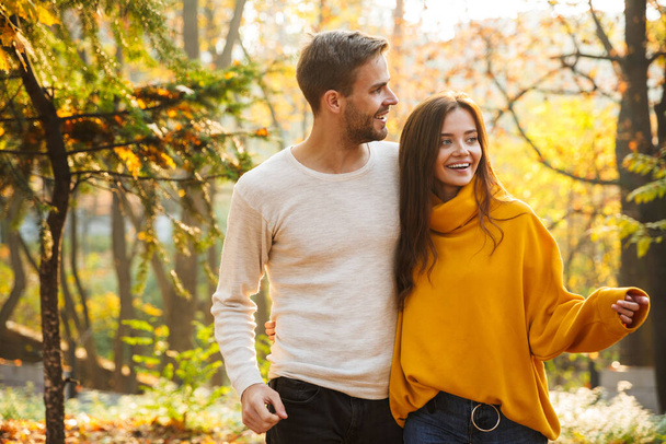 Beautiful young happy couple in love embracing while spending time in the autumn park - Foto, Bild
