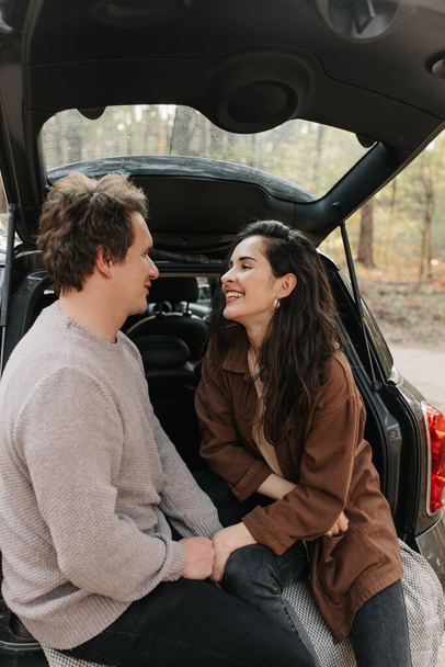 Young beautiful couple relaxing together sitting on a car trunk - Foto, immagini