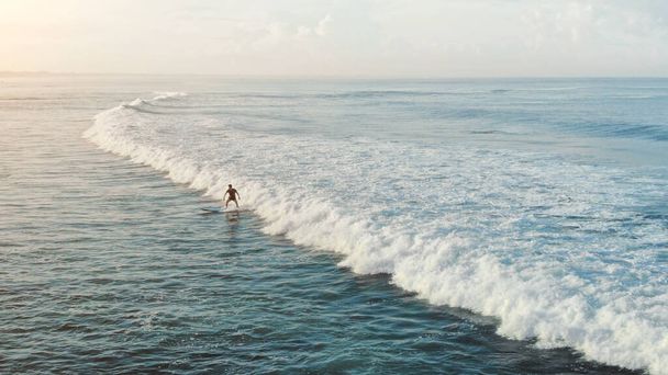 Surfař. Man On White Surfboard Surfing In Ocean. Vodní sporty pro aktivní životní styl. Krásné moře za slunečného dne. - Fotografie, Obrázek
